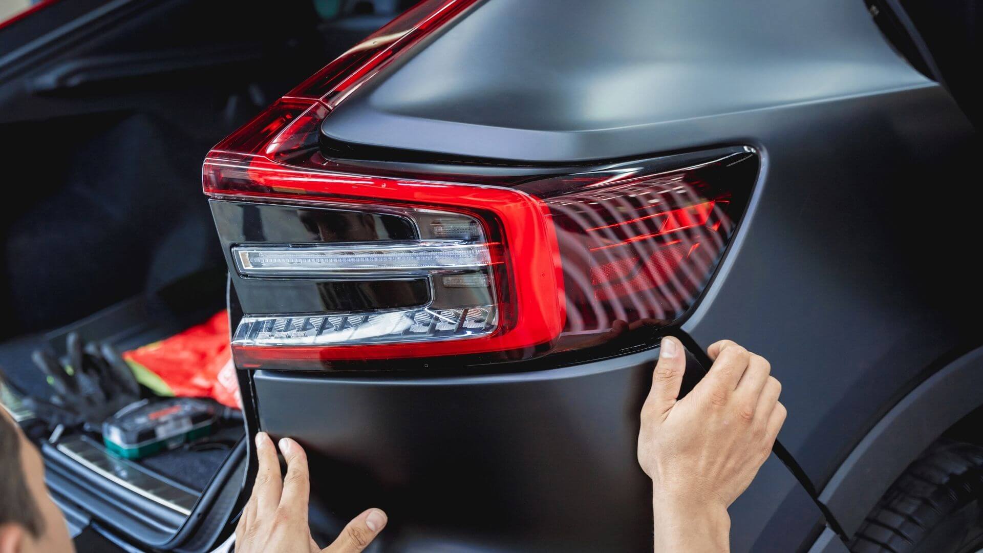 Auto body repair technician installing rear vehicle panel after collision repair in Phoenix, AZ.